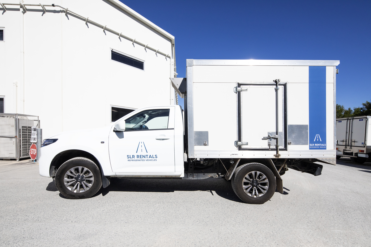 A white refrigerated ute parked next to a building of SLR Rentals and also shows that trusted refrigerated utes rental service for client's seamless experience