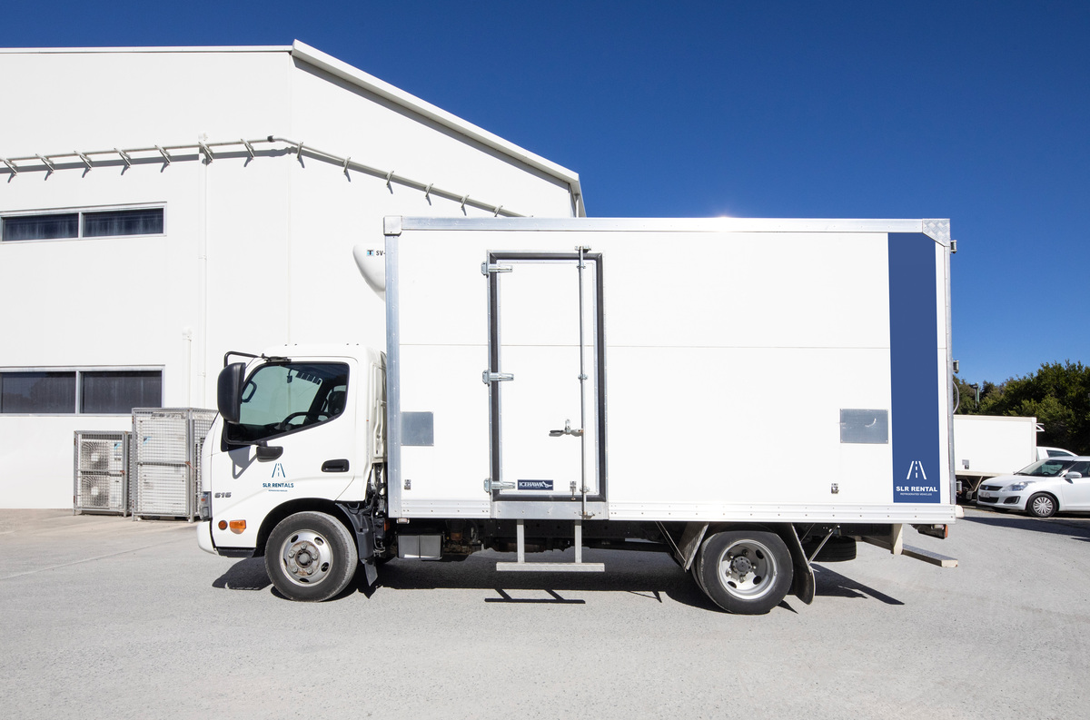 A white refrigerated ute parked next to a building of SLR Rentals and also shows that trusted refrigerated utes rental service for client's seamless experience
